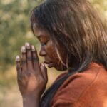 Afro Girl closed her eyes, praying. Hands folded in prayer concept for faith