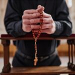 Man with rosary beads praying in church