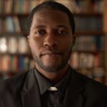 Portrait of Black Priest in Library