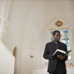 Wide Angle African American Priest Reading Bible at Church Altar